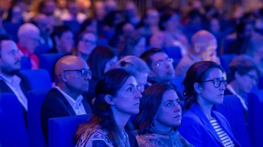 Group of seated delegates in a darkened auditorium