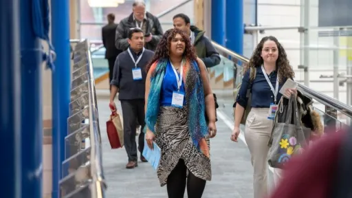 A few people walking along a bridge inside a conference centre