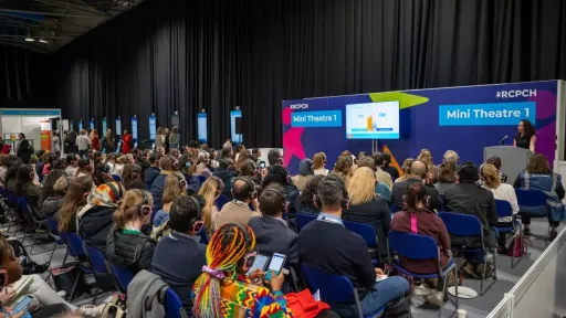 Large group of people wearing headphones and seated to watch a presentation within an exhibition hall