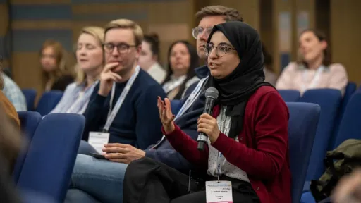 Seated woman in audience speaks into a microphone