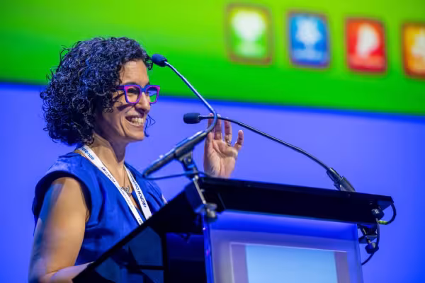 Woman speaking from podium, with a presentation slide in the background